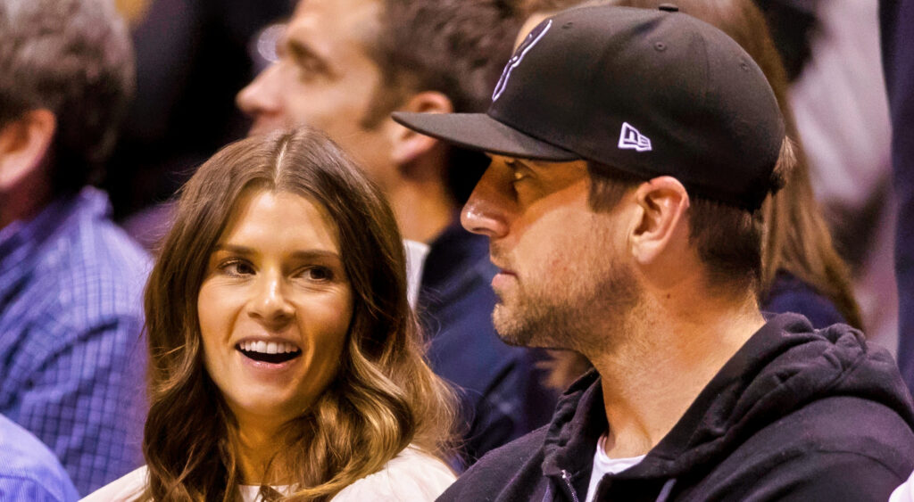 Danica Patrick and Aaron Rodgers watching an NBA game.